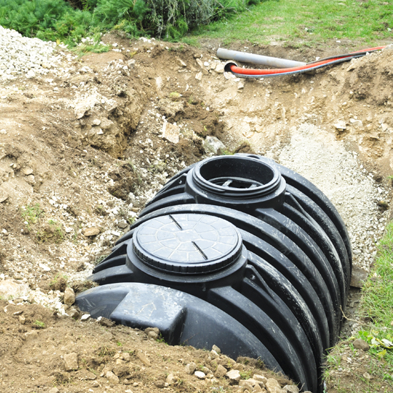A Black Septic Tank Halfway Buried In Dirt Outside